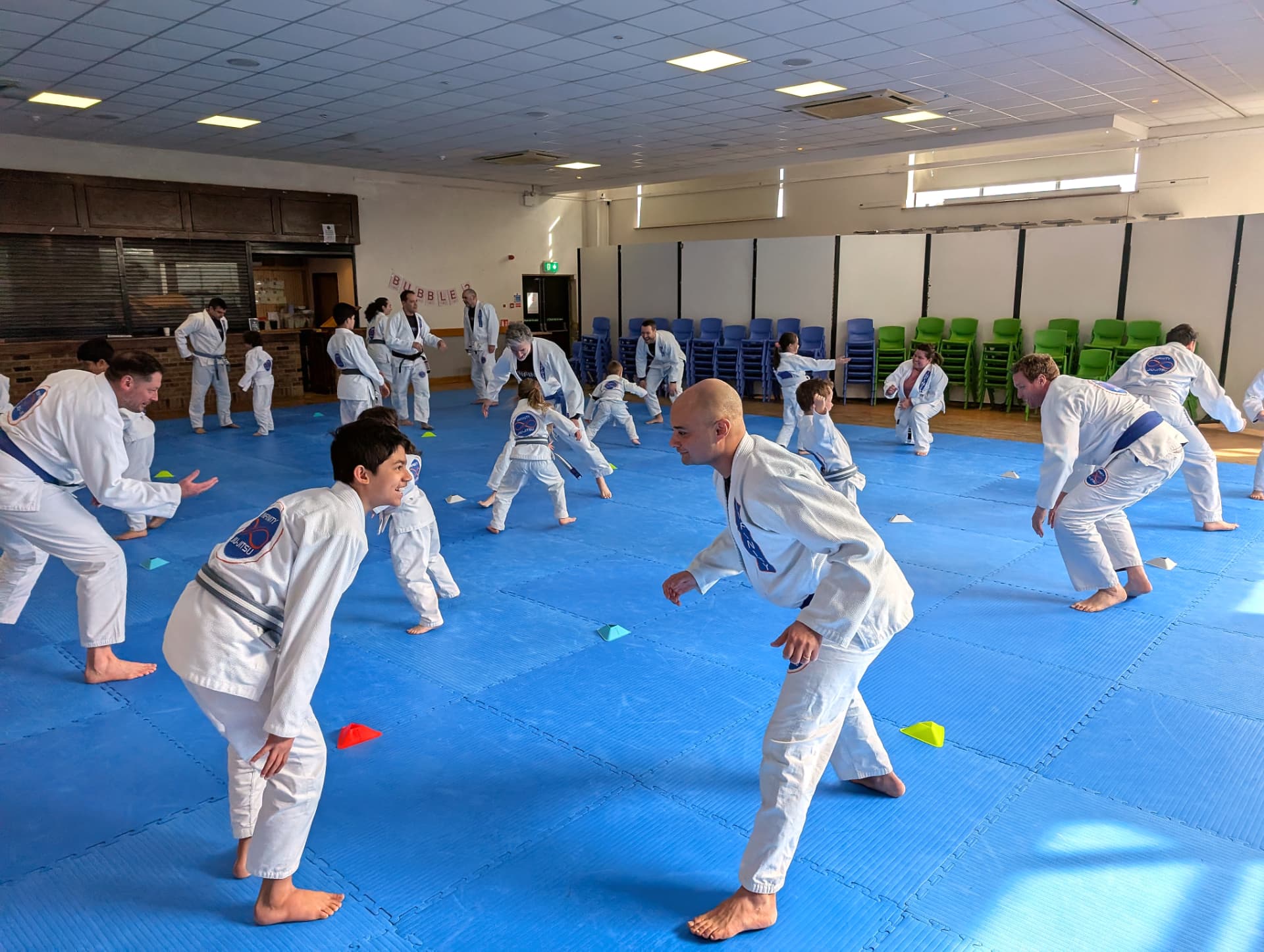 Adults and children warming up together on the mats during a family class